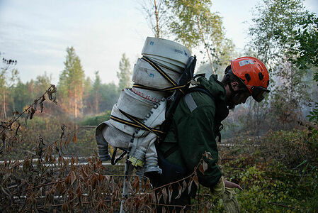 Firefighter carries sleeves to the water