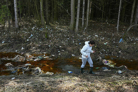 A resident of the village of Khrabrovo near Moscow crosses a stream in the forest near the territory of the landfill.